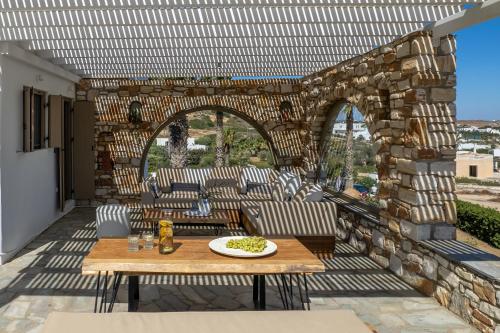 a patio with a table and chairs and a stone wall at Amalgam Homes Paros in Ambelas