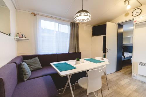 ein Wohnzimmer mit einem lila Sofa und einem Tisch in der Unterkunft Holiday cottage II with 2 Thermal Riviera Tickets in Moravske-Toplice