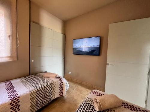 a bedroom with two beds and a television on the wall at Vera-Mojácar Valle del Este Resort Golf & SPA in Vera