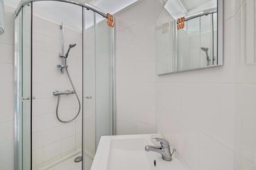 een badkamer met een douche, een wastafel en een spiegel bij Le Milady- Versailles in Versailles