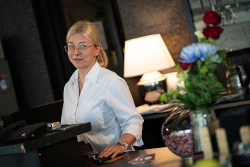 a woman standing at a desk in a hotel room at Hotelli Olof in Tornio