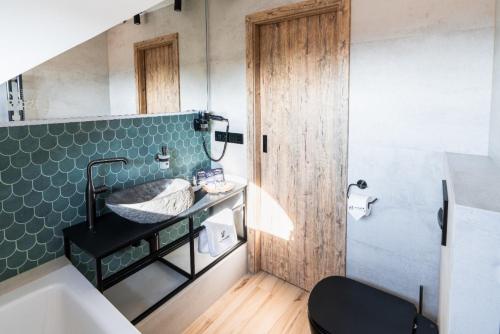 ein Bad mit einem Waschbecken und einer Wand mit grünen Fliesen in der Unterkunft Penzion Monner in Mikulov