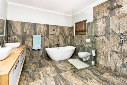 bagno con 2 lavandini, vasca e servizi igienici di Modern 4 bedroom residential villa with pool, fully solar powered a Sandton