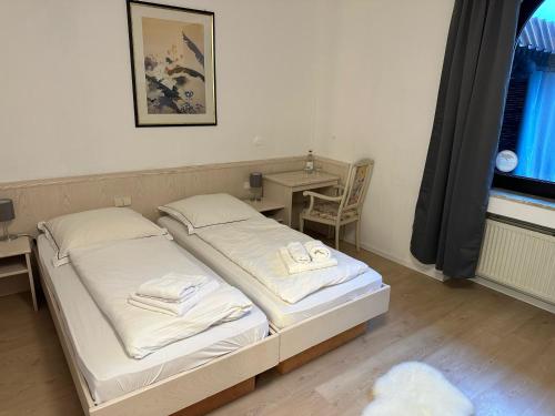 a bedroom with two beds and a desk and a window at Hotel "dream in" Heiligenhaus in Heiligenhaus