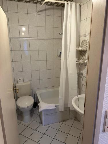 a bathroom with a toilet and a tub and a sink at Hotel "dream in" Heiligenhaus in Heiligenhaus
