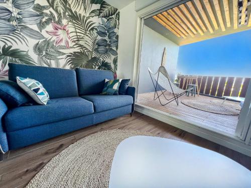 - un salon avec un canapé bleu et une fenêtre dans l'établissement Le Pétrel Bleu - Appartement sur la plage des Tortues à Saint-Leu, à Saint-Leu