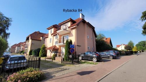 un grupo de autos estacionados frente a una casa en Apartament Rybacka 84/7, en Krynica Morska