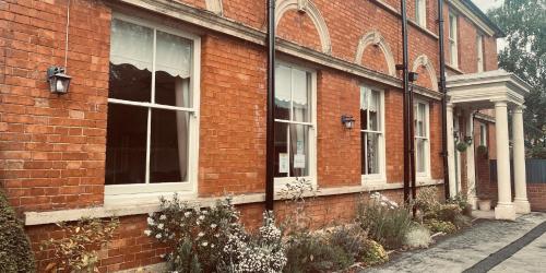 ein rotes Backsteingebäude mit Fenstern auf einer Straße in der Unterkunft Portman Lodge in Blandford Forum