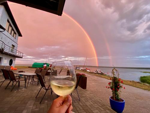 a person holding a glass of wine with a rainbow in the background at Vergi Sadam & Restoran Wirkes' in Vergi