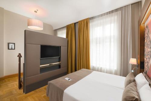 a hotel room with a bed and a flat screen tv at Hotel Moments Budapest by Continental Group in Budapest