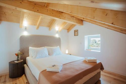1 dormitorio con 1 cama blanca grande y techos de madera en Apartamento Alicante, en Montemor-o-Novo