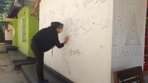 a woman is writing on a wall at HOME HOSTEL ELLA private rooms only in Ella