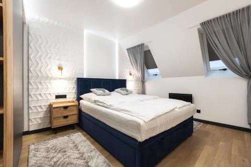 a bedroom with a blue bed in a room with windows at Mountain Apartments Butorowy Residence in Kościelisko