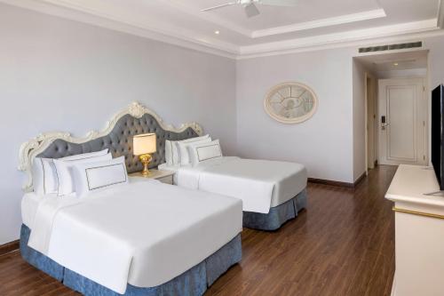 two beds in a room with white walls and wood floors at Melia Vinpearl Tay Ninh in Tây Ninh