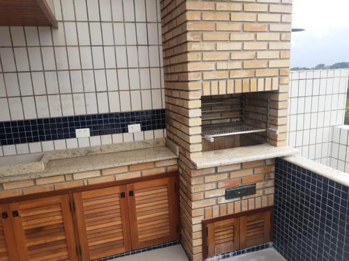 a kitchen with wooden cabinets and a brick wall at Apartamento Duplex pé na areia em Boracéia in Bertioga