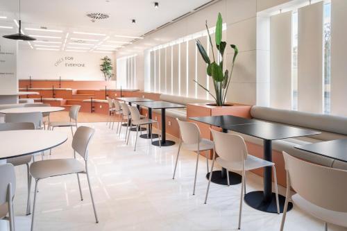 a waiting room with tables and chairs at B&B HOTEL Granada Estación in Granada