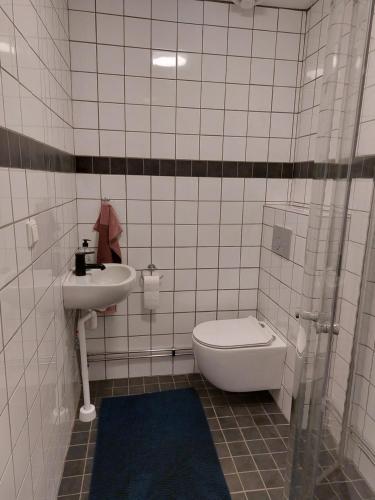 ein weiß gefliestes Bad mit einem WC und einem Waschbecken in der Unterkunft Rumskulla guesthouse in Vimmerby
