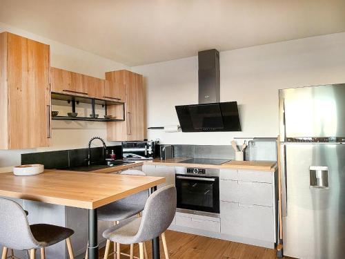 a kitchen with a wooden table and a stainless steel refrigerator at Le Pétrel Bleu - Appartement sur la plage des Tortues à Saint-Leu in Saint-Leu