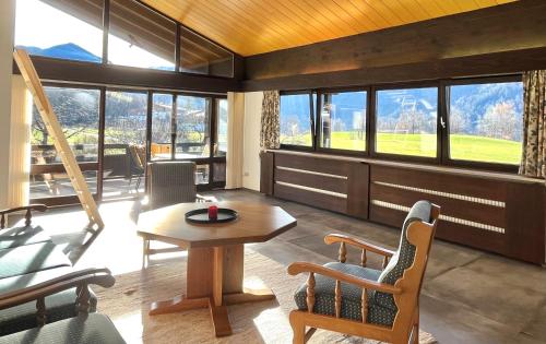 een woonkamer met een tafel, stoelen en ramen bij Hohenwaldeck Seeblickrefugium in Schliersee