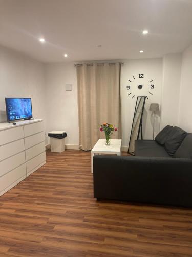 a living room with a couch and a clock on the wall at Lovely luxury 1-Bed Apartment in Wembley in London