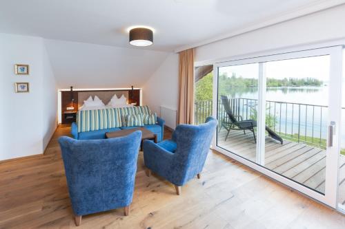 a room with a bed and chairs and a balcony at Hotel Stadler am Attersee in Unterach am Attersee