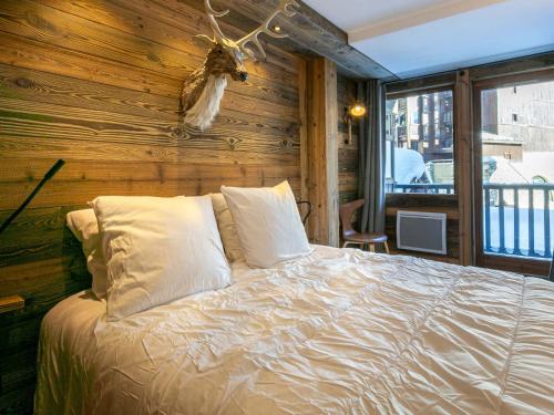 - une chambre avec un lit et un mur en bois dans l'établissement Appartement de prestige au pied des pistes avec wifi, parking couvert, et balcon exposé Est - FR-1-694-153, à Val dʼIsère