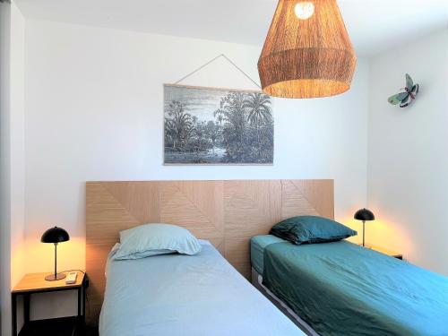 um quarto com 2 camas e uma luz suspensa em BEL' ORIZONTE proche centre ville et plage em Propriano