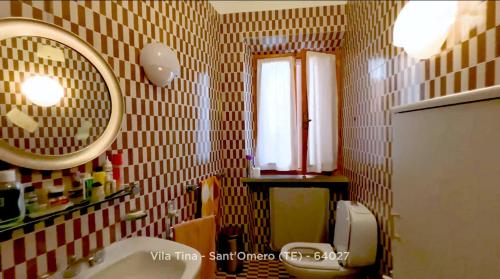 La salle de bains est pourvue d'un lavabo et d'un miroir. dans l'établissement B&B Villa Tina, à SantʼOmero