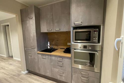cocina con armarios de acero inoxidable y microondas en JPP 1- Zimmer Apartment in Hamburg Farmsen Berne SELF CHECK-IN en Hamburgo