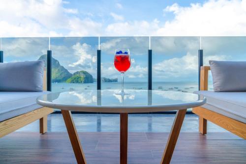 a glass of red wine sitting on a table in front of a window at H Hotel El Nido - Vegan Friendly Hotel Managed by H Hospitality Group in El Nido