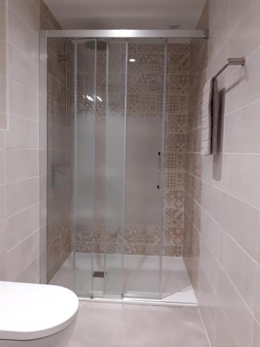 La salle de bains est pourvue d'une douche avec une porte en verre. dans l'établissement Le Moulin du Comte, à Bourrouillan