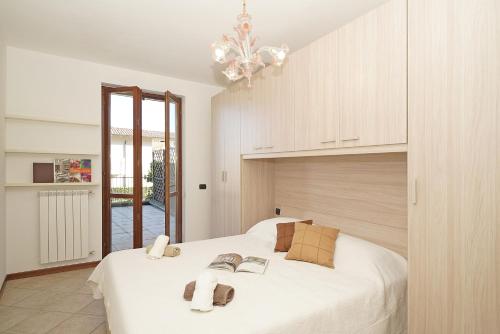 ein Schlafzimmer mit einem großen weißen Bett und einem Kronleuchter in der Unterkunft Appartamento Magenta - Gardagate in Moniga