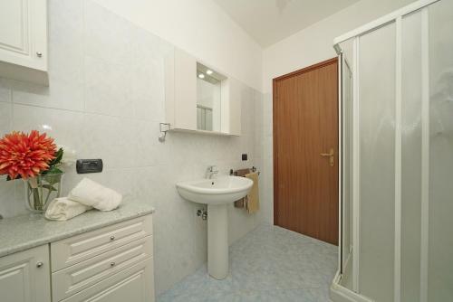 ein weißes Bad mit einem Waschbecken und einer Dusche in der Unterkunft Appartamento Magenta - Gardagate in Moniga