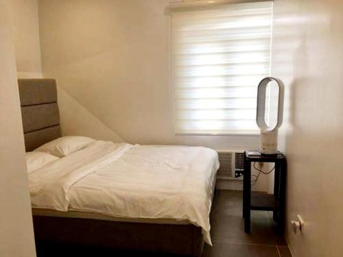 1 dormitorio con cama, espejo y ventana en Cozy Holiday Home at Batulao Artscapes 2Br brand new fully airconditioned, en Calo