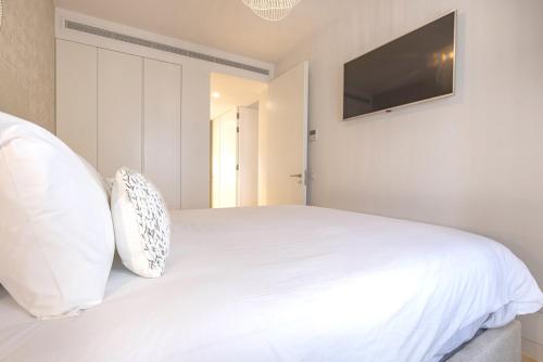 a bedroom with a white bed with a flat screen tv at Ando Living - Douradores House in Lisbon
