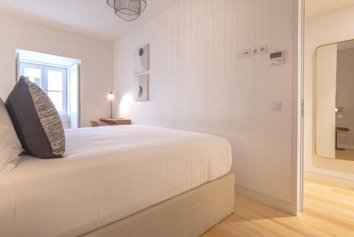 a white bedroom with a bed and a mirror at Ando Living - Douradores House in Lisbon
