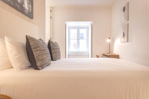 a bedroom with a large white bed with pillows at Ando Living - Douradores House in Lisbon