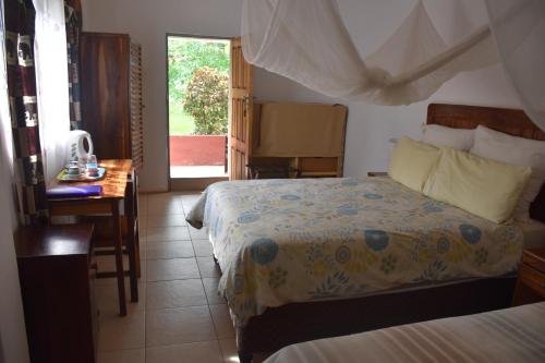 a bedroom with two beds and a desk and a window at Tabonina Guesthouse in Livingstone