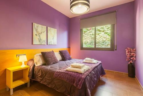 Dormitorio púrpura con cama y ventana en Casa Lourdes en Barcelona