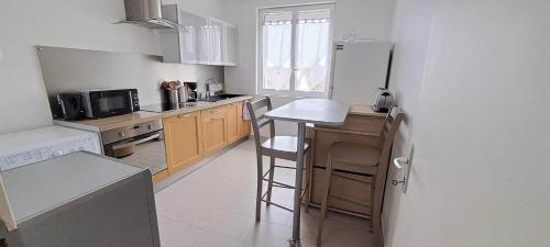 a kitchen with a refrigerator and a counter with a stool at Appartement 3 étoiles de 63m2 in Cabourg