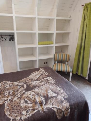 1 dormitorio con cama, silla y estanterías en DELFINS en Mar de las Pampas