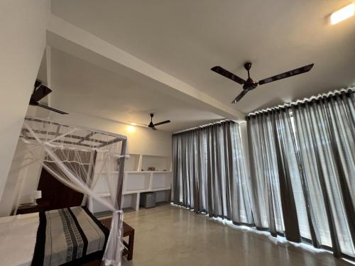 a bedroom with a canopy bed and large windows at Galawatta Beach Resort in Unawatuna