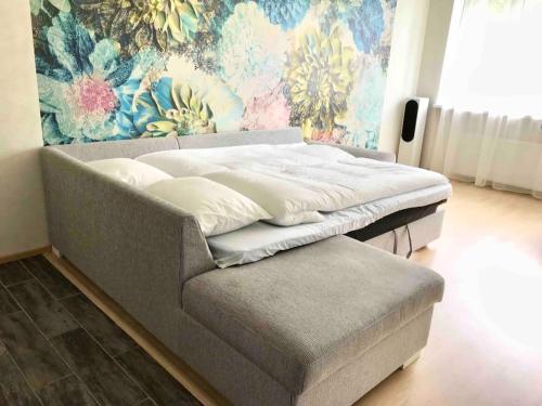 a bed sitting in a room with a couch at Cozy apartment near Lõunakeskus with home cinema in Tartu