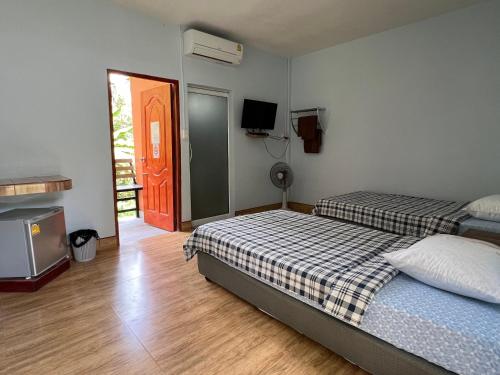 a bedroom with two beds and a television in it at Baan Suan Tondin 