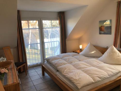 ein großes Bett in einem Zimmer mit einem großen Fenster in der Unterkunft Darsser Weg 34 in Zingst