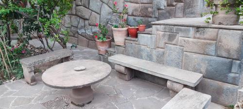 a stone wall with a bench and a table and potted plants at Hospedaje Chaska Pisac in Pisac