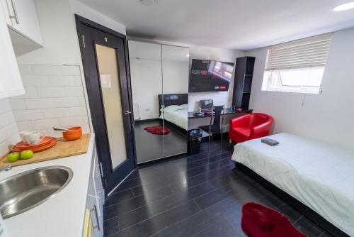 a bathroom with a bed and a sink in a room at Lovely studio close to University of Birmingham! in Birmingham