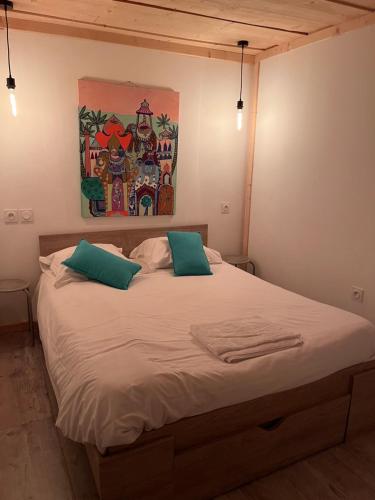 a bed with two pillows and a painting on the wall at Le Gîte les NUZ ( parc du château de Keroüartz) in Lannilis