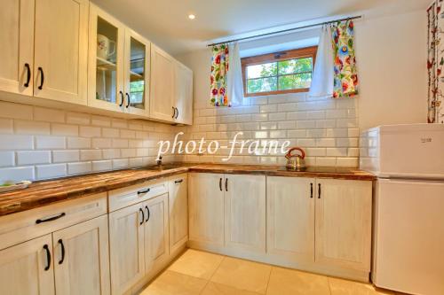 a kitchen with white cabinets and a white refrigerator at Domki całoroczne DOMKOWSTWO in Bóbrka