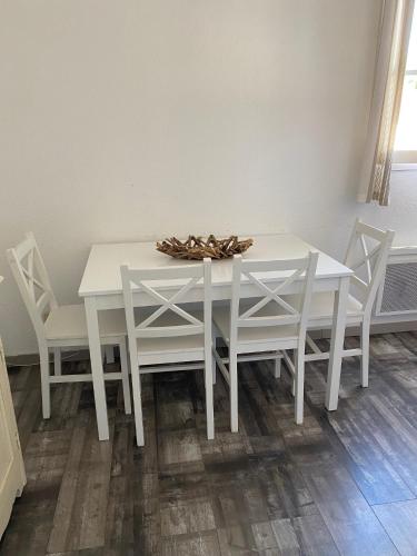 - une table à manger blanche avec des chaises blanches dans l'établissement Les Remparts, à Saint-Martin-de-Ré